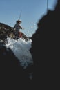 Fisherman in a straw hat with a fishing rod with large waves and rocks Royalty Free Stock Photo