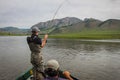 A fisherman with a Taimen Trout on the end of his line in Mongolia, Moron, Mongolia - July 14th 2014 Royalty Free Stock Photo