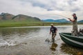 A fisherman with a Taimen Trout on the end of his line in Mongolia, Moron, Mongolia - July 14th 2014 Royalty Free Stock Photo