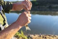 The fisherman takes a crucian fish from a fishing hook, visible hands of a man and a pond in the background.