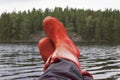 Fisherman taking a break with rubber boots resting on bulwark.