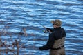 Fisherman in waders catches pike in the lake