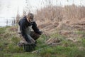 Fisherman in waders prepares bait for catching pike in the river