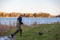 Fisherman in waders comes out of the river to the river bank