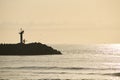 Fisherman walking along the breakwater dawn