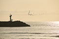 Fisherman walking along the groyne sunrise