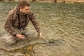 A fisherman watches a chum salmon swim away, after being released back into the river Royalty Free Stock Photo