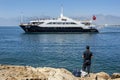 A fisherman watches a cruise ship move through Antalya Bay in Turkey.