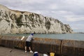 A fisherman watching his fishing rod on the background of white cliffs.