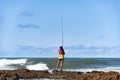 Fisherman woman with fishing rod on the rocks fishing