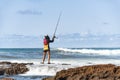 Fisherman woman with fishing rod on the rocks fishing