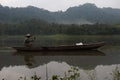 A fisherman, wooden boat, freshwater lake.