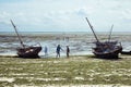 Fishermans burning their traditional African fishing boats on the low tide beach full of seaweed. Zanzibar, Tanzania Royalty Free Stock Photo