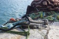 Fishermans equipment lying on the coastline in harbor, heap nylon yellow tangled fishing net in sunlight, colorful ropes