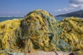 Fishermans equipment lying on the coastline in harbor, heap nylon yellow tangled fishing net in sunlight