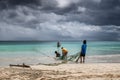 Fishermen on a beach pull nets from the sea in sandy beach with dramatic sky Royalty Free Stock Photo