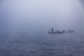 Fishermen catch fish on a boat in the fog in the autumn.