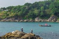 Fishermen catching fish on the rocky tropical beach in Thailand. During sunny day