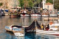 Fishermen check the nets on a fishing boat against the background of recreational ships in vintage style in the ancient harbor in