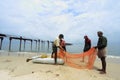 Fishermen clean fish net at seashore