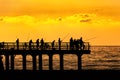 Fishermen crowd silhouette on sunset pier