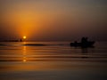 Fishermen in a fishing boat on background of a Golden sunset on sea. Full calm, calm surface of water in ocean with a Royalty Free Stock Photo