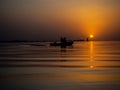 Fishermen in a fishing boat on background of a Golden sunset on sea. Full calm, calm surface of water in ocean with a Royalty Free Stock Photo