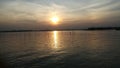 Fishermen fishing in the bright sunset sky with a reflection of the sun on the river bank. Royalty Free Stock Photo