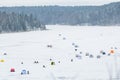 Fishermen fishing on a frozen lake in winter with fishing pole or rod, ice auger, various equipment Royalty Free Stock Photo