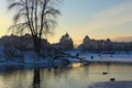 Fishermen are fishing on the frozen part of the Dnieper River. Scenic winter landscape of Obolon neighborhood during sunset.