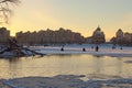 Fishermen are fishing on the frozen part of the Dnieper River. Scenic winter landscape of Obolon neighborhood during sunset.