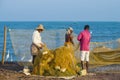 Fishermen with nets on the ocean shore