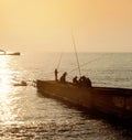 Fishermen on the pier on the background of sunset Royalty Free Stock Photo