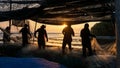 Fishermen pull fishing net at sea coast during sunset