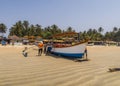 Fishermen pushing a boat into the ocean on a sandy beach in Palolem, Goa, India