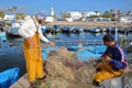 Fishermen repairing their net at the fishing port, with the city of Mahdia in the background