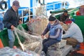 Fishermen repairing their net on their boat at the fishing port, with colorful fishing nets around them