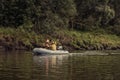 Fishermen sailing on inflatable boat along river bank and fishing with fishing rods Royalty Free Stock Photo
