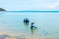 Fishermen stand in sea water and pull a net with fish. The locals are grovelling. Koh Samui, Thailand