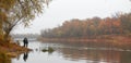 Fishermen stand by the water of a forest lake in autumn.