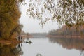 Fishermen stand by the water of a forest lake in autumn.