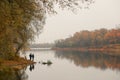 Fishermen stand by the water of a forest lake in autumn.