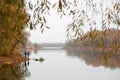 Fishermen stand by the water of a forest lake in autumn.