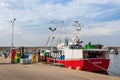 Fishermen unloading a fishing boat at the harbor. Men wearing work uniform, yellow waterproof trousers and plastic boots. Fish is Royalty Free Stock Photo