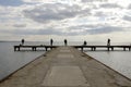 Fishermen waiting on a pier on a winter day. Cloudy sky and calm sea. Royalty Free Stock Photo