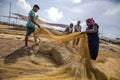 Fishermen and women drag a net filled with dried sardine fish on Negombo beach in Sri Lanka.
