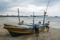 Fishers pulling boat from the shore to the ocean