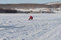 The fisherwoman sits and catches fish on the snowy lake, in the winter day