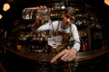 Fisheye shot attractive bartender pouring a cocktail from the measuring cup to the glass