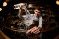 Fisheye shot smiling male bartender pouring a cocktail from the measuring cup to the glass